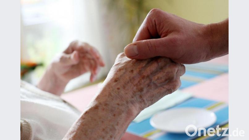 Ein Pfleger drückt die Hand eines pflegebedürftigen Menschen. Nähe ist in der Pflege unabdingbar. &quot;Dazu gibt es keine Alternative&quot;, sagt Wolfgang Rattai, der das Marienheim der Caritas in Amberg leitet. Symbolbild: Oliver Berg/dpa