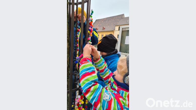 Voller Eifer knüpfen die Kinder der Kita-Notgruppe insgesamt 10 246 flauschige Pompons an die Bäume am Schnaittenbacher Marktplatz. Damit sorgen sie für kleine, knallbunte Hingucker und für freudige Momente im Corona-Lockdown. Bild: ads