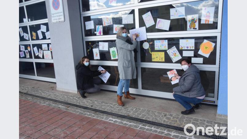 Doris Völkl, Andrea Reinold und Susanne Wirth (von rechts) heften 78 Faschingsbilder der Kinder an die Tore des Feuerwehrhauses. Bild: fz