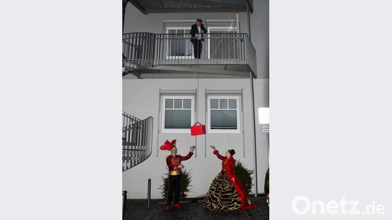 Fasching mit Abstand: Rebecca I. und Manuel I. geben die Stadtkasse zurück, dafür lässt Bürgermeister Karlheinz Budnik ein langes Seil vom Balkon. Bild: exb