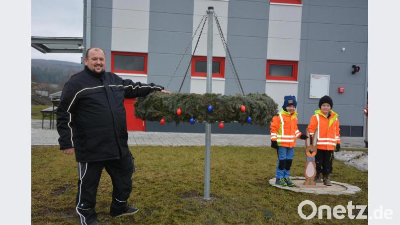 Die Feuerwehr Groschlattengrün um Vorsitzenden Markus Spörrer will den Adventskranz vor dem Gerätehaus in einen Osterkranz verwandeln und ruft Kinder zur Unterstützung auf. Paul und Valentin (von rechts) haben am Samstag bereits erste Ostereier angebracht und einen Osterhasen aufgestellt. Bild: jr