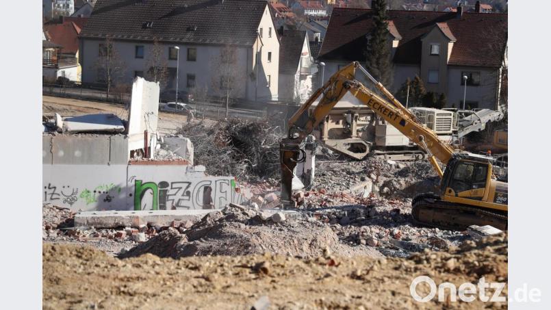 : Mit einem Hydraulikmeißel wird das massive Fundament zerkleinert, während dahinter der Brecher die Betonbrocken für das Recycling zerkleinert. Bild: cog