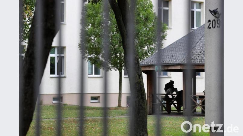 Ein Asylsuchender sitzt vor einem Wohnblock im Ankerzentrum Schweinfurt. Symbolbild: Karl-Josef Hildenbrand/dpa