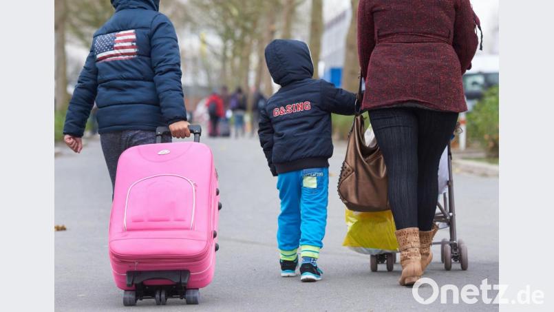 Eine Flüchtlingsfamilie mit Koffer und Kinderwagen. Symbolbild: Bernd Thissen/dpa