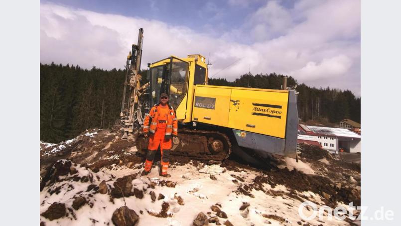 Mit dem Bohrgerät treibt Sprengmeister Martin Schaller von der Firma Seebauer Tiefbau GmbH die Löcher für den Sprengstoff in den harten Granit. In Sichtweite zur Firma Weinfurtner (rechts) wird am Dienstagnachmittag die oberste Kuppe des 18 Meter hohen Felsentors weggesprengt. Bild: Portner