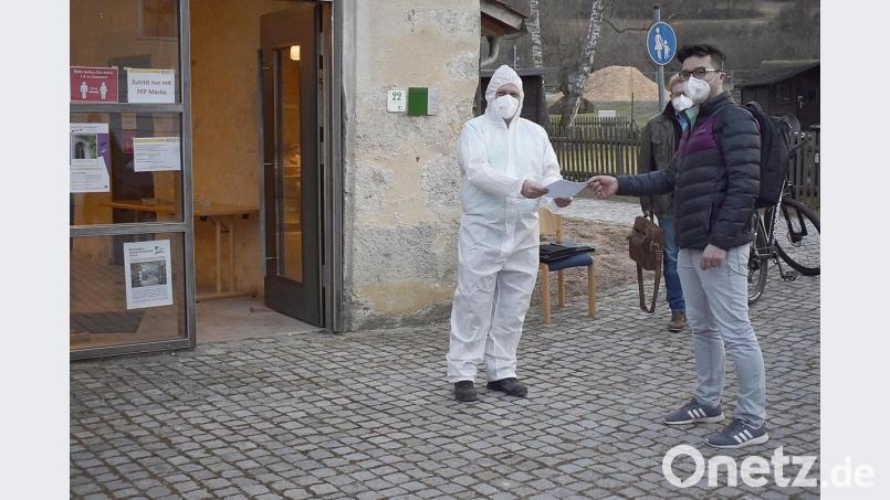 ASB-Geschäftsführer Andreas Brunner (links) übergibt die Bestätigung über sein negatives Testergebnis an den stellvertretenden Bürgermeister Christian Hirsch. Im Hintergrund Bürgermeister Bernhard Köller. Bild: sck
