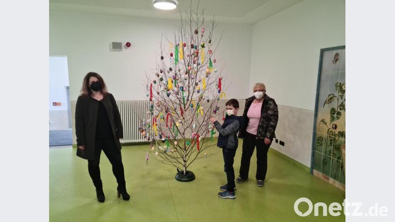 Verbindungslehrerin Annika Heisig (links) hatte die Osterbaumaktion organisiert und St. Sebastian-Heimleiterin Brigitte Adam den Baum übergeben. Adams Enkel Maximilian hängt noch schnell ein selbst gestaltetes Ei hin. Bild: sne