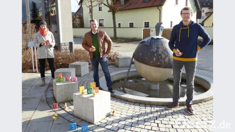 Organisatorin Doris Troglauer und Teamführer Konrad Braun vom Jugendgremium der Gemeinde präsentieren mit Bürgermeister Dietmar Schaller (von links) am Ortsbrunnen ihre Osteridee. Bild: fsb