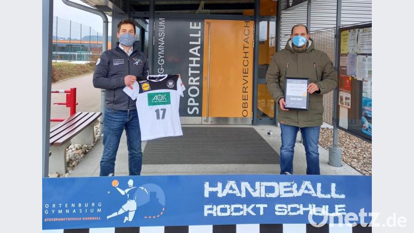 Sportlehrer Michael Teplitzky (links) zeigt das T-Shirt mit den Unterschriften der Herren-Nationalmannschaft. Handballchef Michael Lang präsentiert die Urkunde, mit der der Deutsche Handballbund das innovative und kreative Vereinsengagement würdigt. Bild: lg