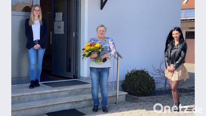 Pflegedienstleiterin Julia Matzke (links) und ihre Stellvertreterin Isabel Meyer (rechts) verabschieden Christa Rumpler mit Dankesworten und einem Blumenstrauß in den Ruhestand. Bild: fdl