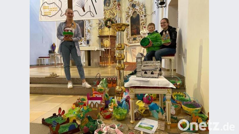 Über die zahlreichen fantasievoll gebastelten Osternester vor dem Altar freuen sich seitens der Katholischen Jugend Julia Bauriedl (links) und Marie Hummer mit Bruder Max. Bild: gz