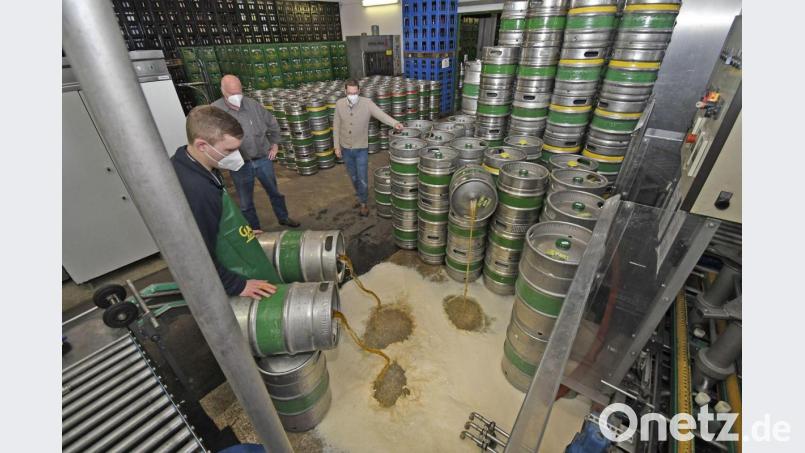 Das Bier fließt in Strömen in den Gully - und den Verantwortlichen der Gambrinus-Brauerei (Geschäftsführer Steffen Hartmann und Heiner Nachtmann, von rechts) schießen die Tränen in die Augen. Brauer Jens Rittersbacher (links) arbeitet beim Entleeren der 50-Liter-Fässer beidhändig. Bild: Petra Hartl