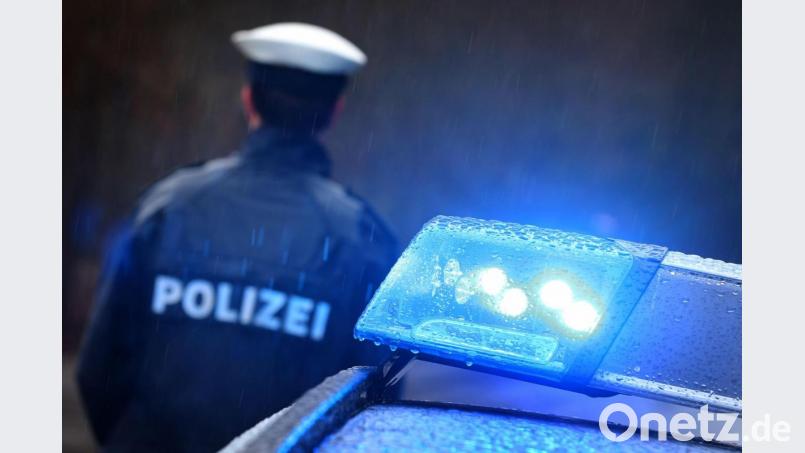 Ein Polizist steht im Regen vor einem Streifenwagen dessen Blaulicht aktiviert ist. Symbolbild: Karl-Josef Hildenbrand/dpa