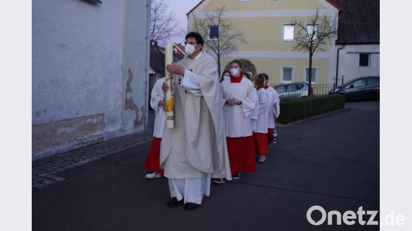 Pfarrer Wolfgang Dietz mit der am Feuer entzündeten Osterkerze vor dem Einzug in die Pfarrkirche. Bild: mmj