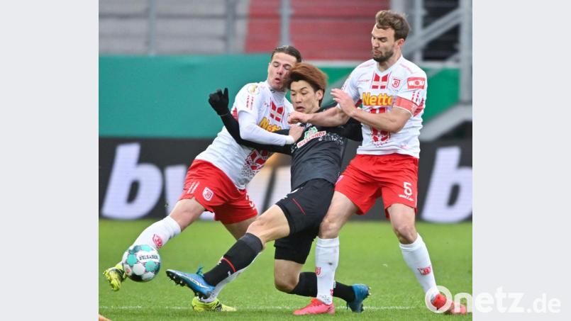 Kampf war Trumpf zwischen dem SSV Jahn Regensburg und Werder Bremen. In dieser Szene nehmen Jan Elvedi (links) und Benedikt Gimber (rechts) den Bremer Yuya Osako in die Zange. Bild: Armin Weigel/dpa