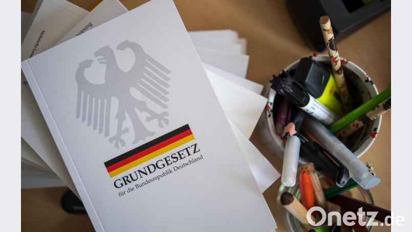 Eine Ausgabe des Grundgesetzes der Bundesrepublik Deutschland liegt während des Unterrichts auf einem Tisch neben Schreibutensilien. Symbolbild: Monika Skolimowska/dpa
