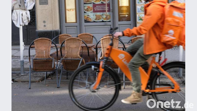 Der Fahrer eines Lieferdienstes fährt an dem Freisitz eines geschlossenen Restaurants vorbei. Bild: Sebastian Willnow/dpa