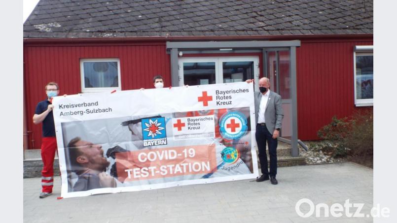 Vor dem Kümmersbrucker Testzentrum, dem Martin-Schalling-Haus in der Schillerstraße 3, rollen die Vertreter von BRK und Wasserwacht das Hinweisbanner schon mal probeweise auf. Bild: e