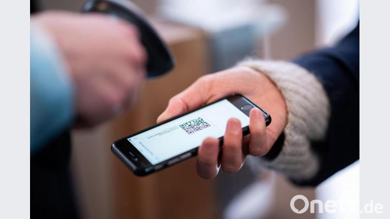 Eine Frau lässt am Eingang eines Corona-Schnelltest-Zentrums einen QR-Code auf ihrem Smartphone abscannen. Bild: Daniel Reinhardt