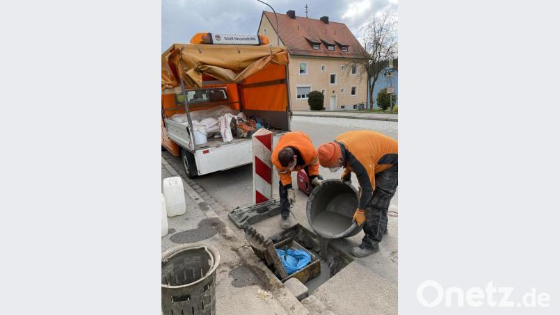 Martin Kißler (links) und Fabian Stich (rechts) beim Ausbetonieren des Sinkkastens im Gully mit dem Kinderhüpfball als Spezialkissen. Bild: Stadt Neustadt/WN/exb