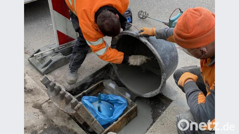 Martin Kißler (links) und Fabian Stich (rechts) beim Ausbetonieren des Sinkkastens im Gully mit dem Kinderhüpfball als Spezialkissen. Bild: Stadt Neustadt/WN/exb