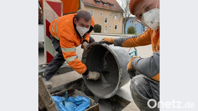 Martin Kißler (links) und Fabian Stich (rechts) beim Ausbetonieren des Sinkkastens im Gully mit dem Kinderhüpfball als Spezialkissen. Bild: Stadt Neustadt/WN/exb