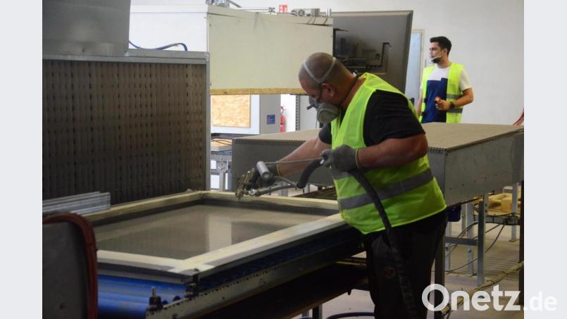 Ein Mitarbeiter trägt auf dem kaputten Solarmodul eine neue Kunststoffschicht auf und macht es so wieder fit. Bild: Kunz