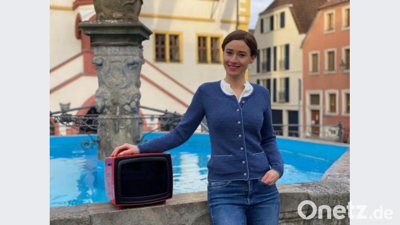 In &quot;Was uns bewegte&quot; begibt sich Miriam Ferstl auf Zeitreise in das Jahr 1971. Immer mit dabei ist ein roter Retro-Fernseher. Bild: exb/Jonas Gernstl
