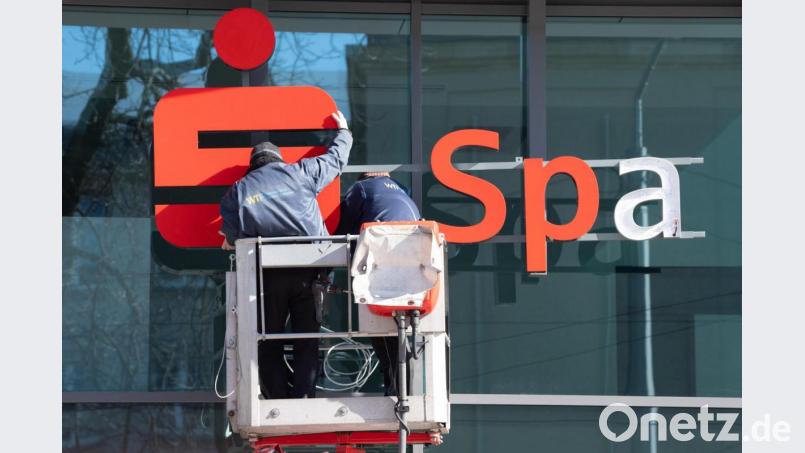 Die Sparkassen kommen bisher besser durch die Corona-Krise als befürchtet: Zwei Werbetechniker installieren mit einer Hebebühne ein Logo der Sparkasse an einer Glasfassade. Bild: Sebastian Kahnert/dpa