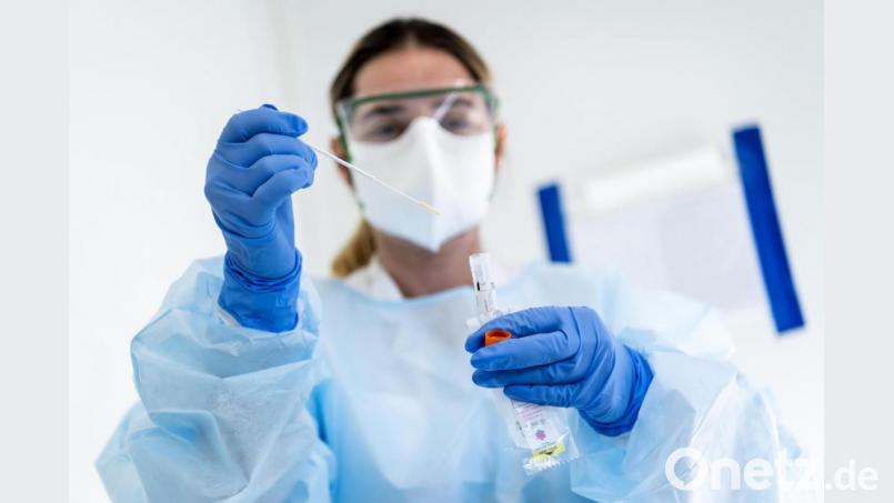 Eine Krankenschwester steckt eine Probe mit einem Nasenabstrich eines Patienten, der auf das Coronavirus getestet wird, in einen Behälter. Symbolbild: Jean-Christophe Bott/KEYSTONE/dpa