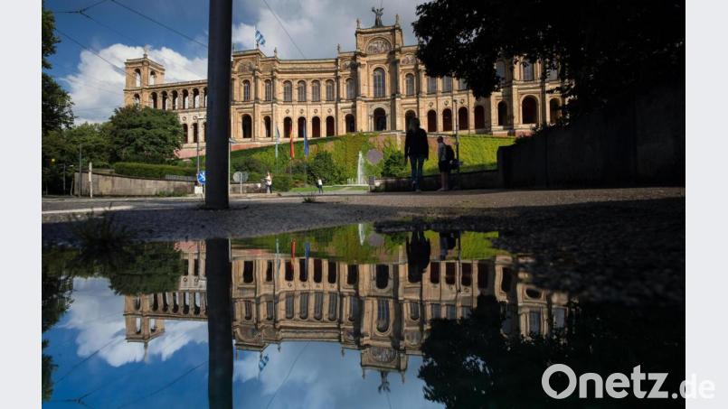 Das Maximilianeum, das den bayerischen Landtag beherbergt, spiegelt sich in einer Pfütze auf der nassen Straße. Archivbild: Peter Kneffel/dpa