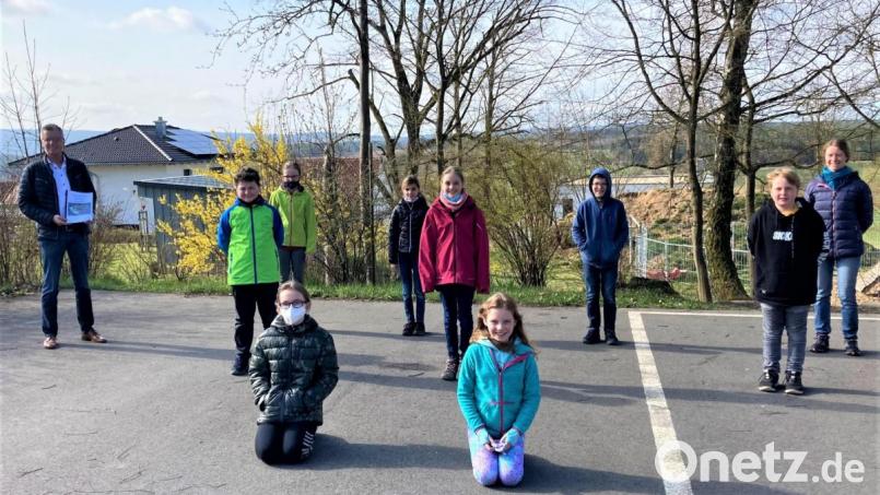 Die anwesenden Kinder der 4. Klasse – die 3. Klasse befindet sich im Moment noch im Distanzunterricht – präsentieren Bürgermeister Hermann Falk (links) stolz ihr Werk, das sie mit Sophie Högl (rechts) selbst geschrieben und gestaltet haben. Bild: Reindl Monika/exb