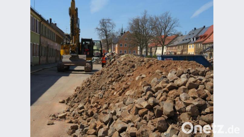 Beim Aufreißen des Asphalts kommen jede Menge Basaltbrocken zu Tage. Mit diesen Kulmsteinen hatten die Neustädter in früheren Jahren den Untergrund des Ortszentrums befestigt. Im Hintergrund ist die Maschine mit der modernen GPS-Baggersteuerung zu sehen. Bild: ow