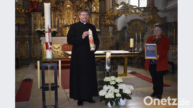 Brigitte Neugebauer übergibt die von ihr verzierte Kerze zur Gebetsstaffel des Seelsorgebereichs an Pater Marek Flasinski. Bild: sck