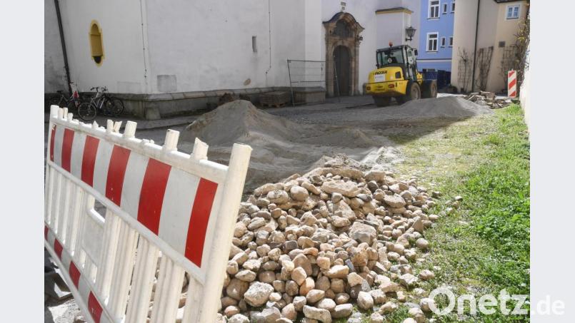 Der Kieselstein-Belag vor dem Haupteingang der Michaelskirche ist beiseite geräumt. Bagger der Baufirma Schieder aus Bechtsrieth graben sich in den Untergrund. Zunächst werden die Entwässerungsleitungen erneuert. Bild: Gabi Schönberger