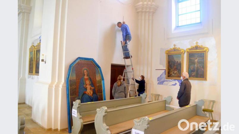 Pfarrer Georg Hartl (rechts) lässt sich die Rückkehr und Montage des aufwendig restaurierten Mariengemäldes (links) durch die Mitarbeiter der Fachwerkstatt Rappenegger auf seinen alten Platz in der Emmeramskirche nicht entgehen. Bild: fjo