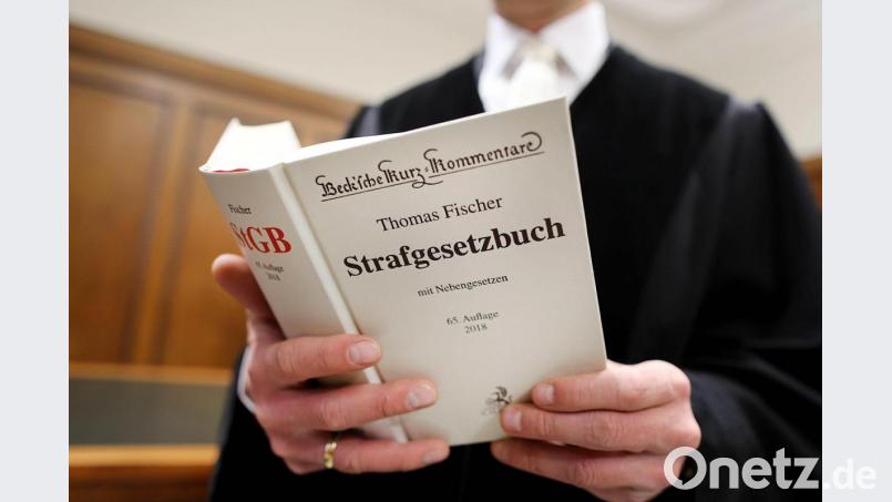 Ein Richter mit dem Strafgesetzbuch (StGB). Bild: Oliver Berg/dpa