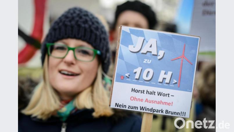 Einer Legende zufolge soll Horst Seehofer auf die 10-H-Regelung gekommen sein, als er mit seinem Dienstwagen an einer Gruppe Windkraftgegner vorbeifuhr, seinen Chauffeur halten ließ und mit den Demonstranten diskutierte. Im Bild: Eine Gegnerin des Ausbaus der Windenergie in Bayern demonstriert am 15. Februar 2014 vor Beginn des kleinen Parteitages der CSU in Bamberg (Bayern) mit einem Schild mit der Aufschrift &quot;Ja zu 10 H - Horst halt Wort - ohne Ausnahme ! Nein zum Windpark Brunn!!!&quot;. Bild: David Ebener/dpa