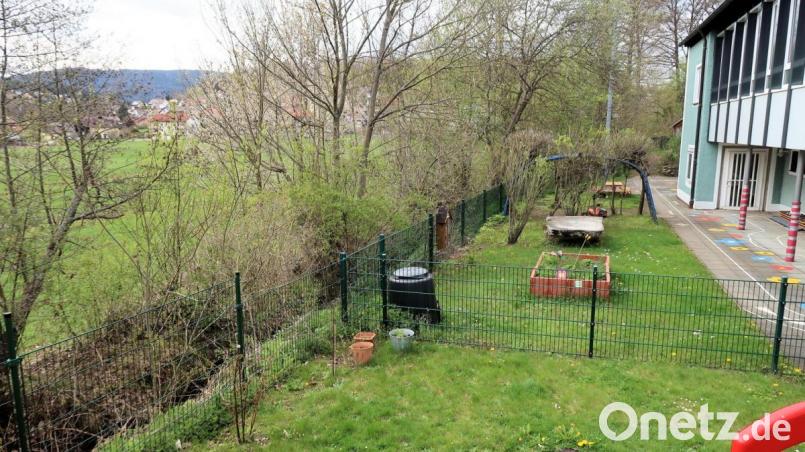 Ein Teil des Grundstücks links vom Zaun gehört der Gemeinde Friedenfels. Diese Fläche könnte während der Umbauarbeiten am Kinderhaus (rechts) als Ersatzspielgarten dienen. Das Erreichen wäre mit dem Bau einer kleinen Brücke über den Bach kein Problem, meint Bürgermeister Oskar Schuster. Bild: bsc