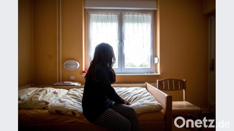 Eine Frau sitzt in einem Frauenhaus auf einem Bett. Rein rechnerisch steigt die Zahl der Plätze im Frauenhaus im Landkreis Schwandorf. Symbolbild: Maja Hitij/dpa
