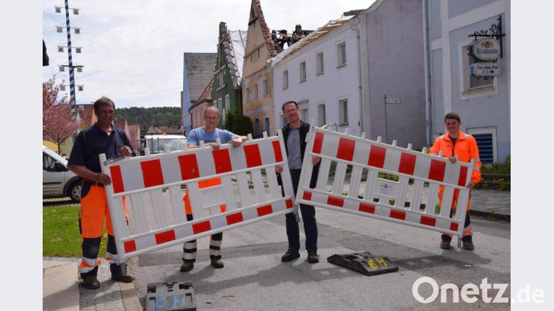 Nach fast einem Jahr wird rechtzeitig zum Vatertag am Marktplatz in Hohenburg die Straßenabsperrung abgebaut. Damit ist auch die Umleitung des Verkehrs der Staatsstraße 2235 über die Vorplätze der Häuser passé. Bürgermeister Florian Junkes (Zweiter von rechts) räumt zusammen mit Bauhofmitarbeitern die Absperrung weg. Bild: bö