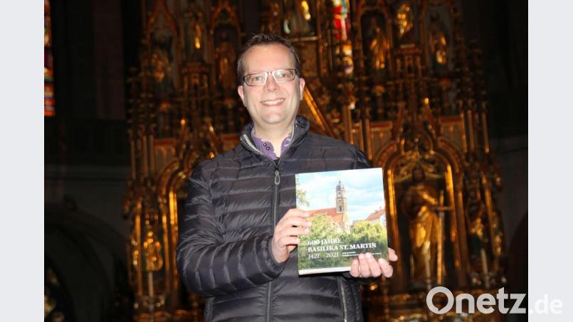 Stadtpfarrer Thomas Helm mit der druckfrischen Jubiläumschronik St. Martin, die anlässlich des 600. Jahrestags der Grundsteinlegung der Martinskirche aufgelegt wurde. Bild: ads
