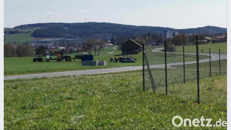 Der Zaun am Solarpark Oberviechtach 1 steht seit einigen Tagen. Auf der Wiese gegenüber (beim Traktoren-Gespann) soll an der Kreisstraße nach Wildeppenried der Solarpark 2 entstehen. Die Änderung des Flächennutzungsplans und auch der vorhabenbezogene Bebauungsplan haben den Stadtrat passiert. Bild: Portner