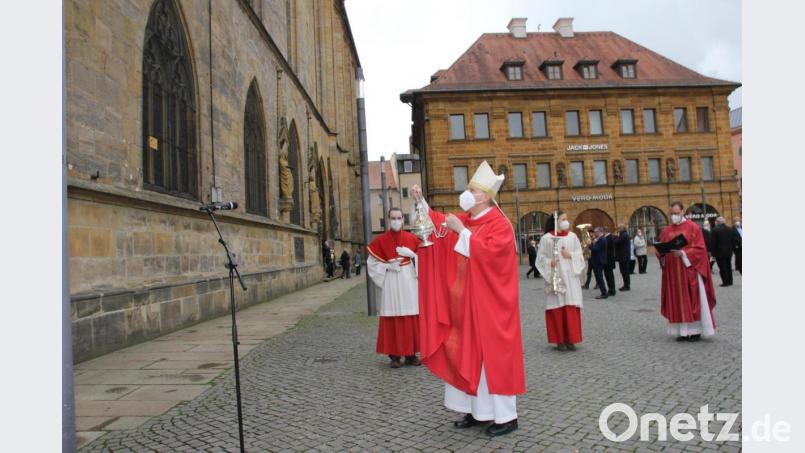 Zum Abschluss der Feier zur Grundsteinlegung von St. Martin vor 600 Jahren ging es im Kirchenzug auf den Marktplatz hinaus, wo Weihbischof Pappenberger den neu restaurierten Gedenkstein an der Fassade segnete. Bild: ads