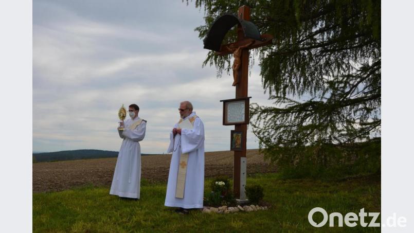 Pfarrseelsorger Pater Benedikt Leitmayr (rechts) und Diakon Bastian Neumann beim Segensgebet am „Grüner Feldkreuz“, das nach einem Unfall am Karsamstag wieder aufgestellt wurde. Bild: jr