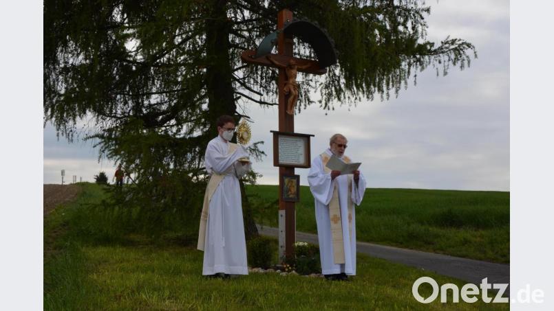 Pfarrseelsorger Pater Benedikt Leitmayr (rechts) und Diakon Bastian Neumann beim Segensgebet am „Grüner Feldkreuz“, das nach einem Unfall am Karsamstag wieder aufgestellt wurde. Bild: jr