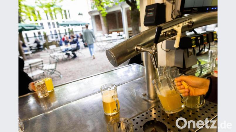 Die Thekenkraft eines Biergartens zapft ein Bier, während im Hintergrund Gäste und Personal des Biergartens zu sehen sind. Bild: Philipp von Ditfurth/picture alliance/dpa