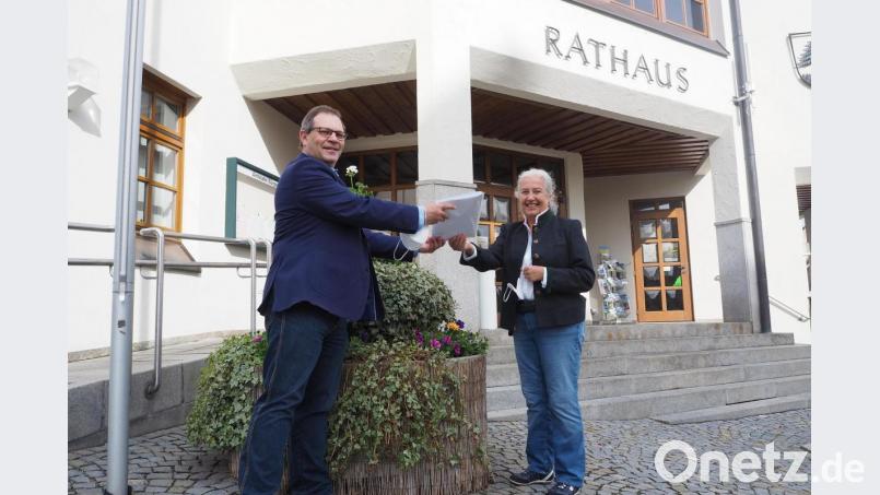 Vor dem Rathaus nimmt stellvertretender Bürgermeister Egbert Völkl (links) die 68 Seiten mit insgesamt 680 Unterschriften gegen weitere Freiflächen-Photovoltaik-Anlagen in Oberviechtach von Hildegard Bücherl entgegen. Bild: bl