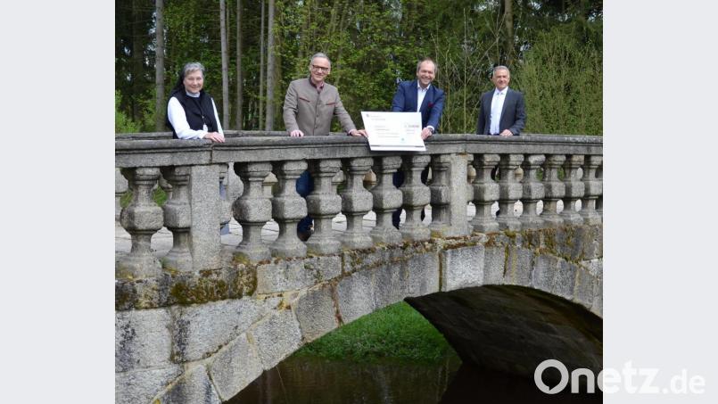 Äbtissin Laetitia Fech, Bürgermeister Bernd Sommer, Hans-Jörg Schön und Landrat Roland Grillmeier (von links) bei der Übergabe des Schecks. Bild: Sr. M. Sophia Schlembach/Kloster Waldsassen/exb