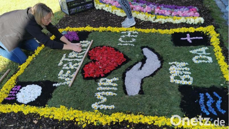 Ein Blumenteppich als besondere Handschrift für Fronleichnam in Corona-Zeiten. Manuela Klug legt in Eslarn die letzten Buchstaben. Bild: gz
